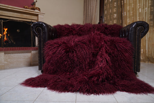 Mongolian Blanket Throw Burgundy — Wool Sheepskin Full Skin spread across the leather sofa showing the whole deep oxblood burgundy Mongolian wool surface — Greek craftsmanship, TatiFurs