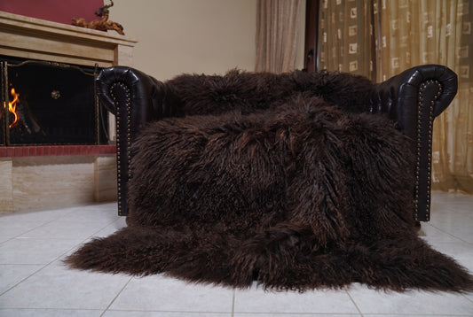 Mongolian Blanket Throw Dark Brown — Wool Sheepskin Full Skin spread across the leather sofa showing the whole deep espresso dark brown Mongolian wool surface — Greek craftsmanship, TatiFurs