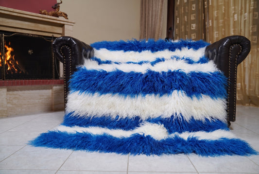 Mongolian Blanket Throw Blue White Striped — Wool Sheepskin spread across the leather sofa showing the whole cobalt blue and pure white Mongolian wool surface — Greek craftsmanship, TatiFurs