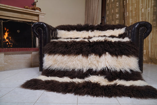 Mongolian Blanket Throw Dark Brown Cream Beige Striped spread across the leather sofa showing the whole espresso brown and cream beige Mongolian wool surface — Greek craftsmanship, TatiFurs