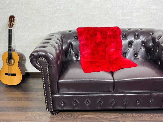 Rex Rabbit Blanket Throw Full Skin Red - Tatifurs on a leather sofa next to an acoustic guitar.