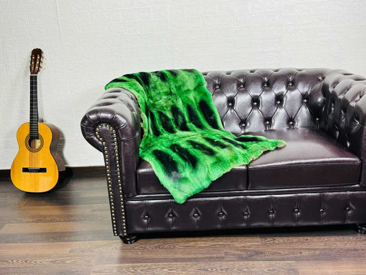 Rex Rabbit Blanket Throw Full Skin Green Black Spots draped over a leather couch with a guitar nearby.