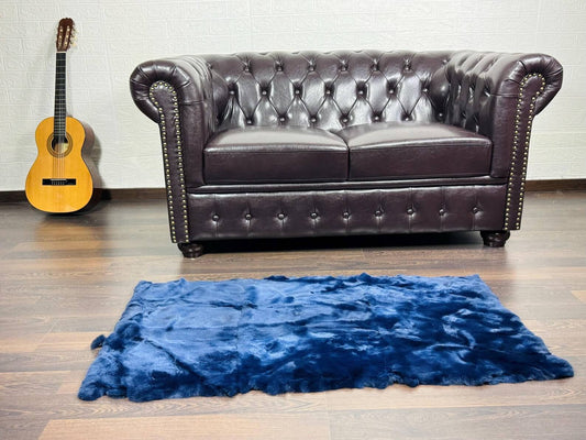 Rex Rabbit Blanket Throw Full Skin Blue - Tatifurs displayed on a modern living room floor with a leather sofa.