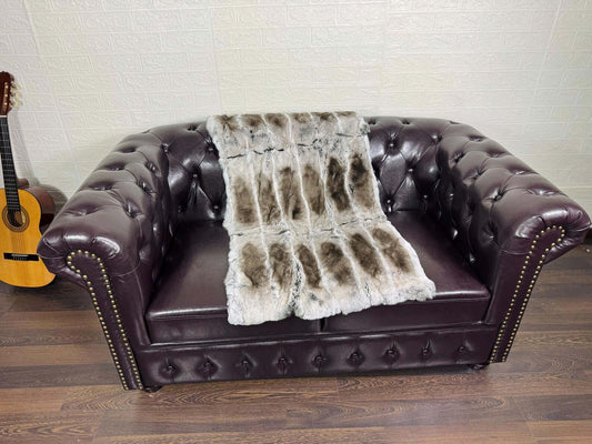 Rex Rabbit Blanket Throw Full Skin Gray Brown displayed on a plush brown couch.