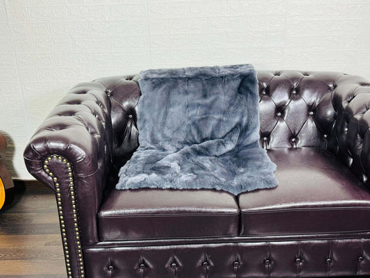 Rex Rabbit Blanket Throw Full Skin Gray - Tatifurs on a leather sofa, showcasing its luxurious texture and color.