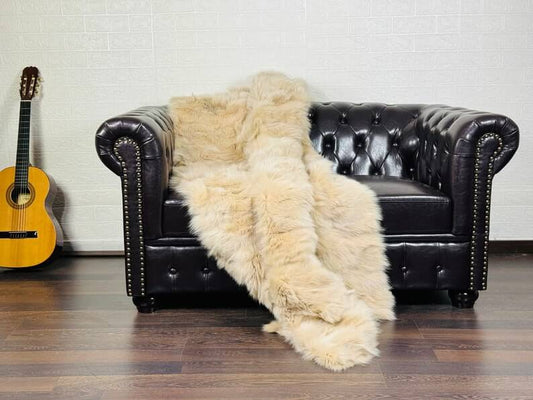 Luxury beige fox fur blanket draped over a linen sofa showing warm neutral tones