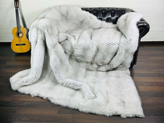 Fox Fur Blanket Throw Blue Natural - Tatifurs on a sofa with an acoustic guitar in the background.