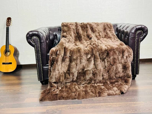 Rabbit Blanket Throw Rex Brown - Tatifurs draped on a vintage leather couch, showcasing its luxurious softness and texture.