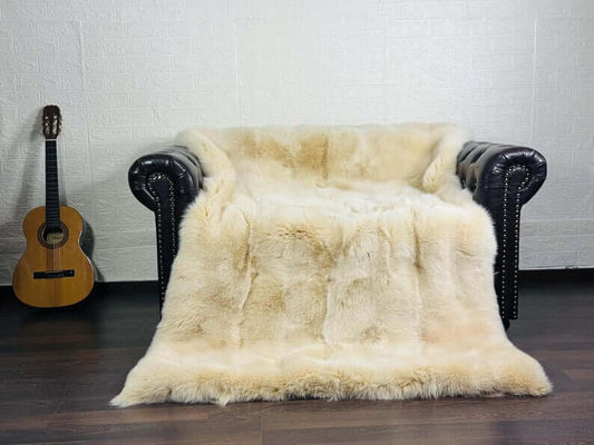 Fox Fur Blanket Throw Beige Ivory - Tatifurs draped over a stylish black leather couch, adding warmth and elegance.