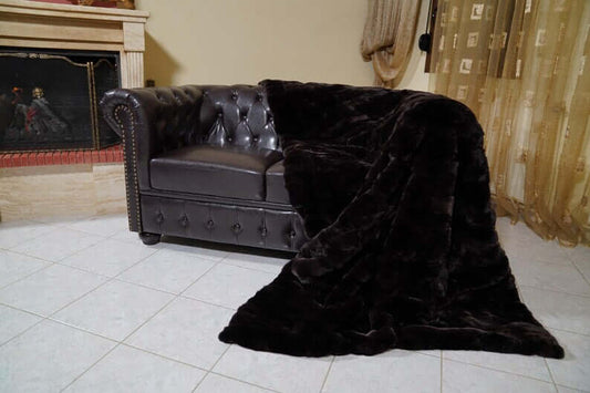 Rabbit Blanket Throw Rex Dark Brown - Tatifurs draped on a luxurious leather couch, showcasing its rich color and softness.