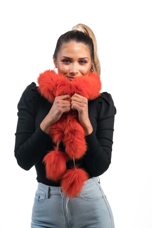 Woman wearing orange fox fur scarf with pom poms showing vibrant fiery color