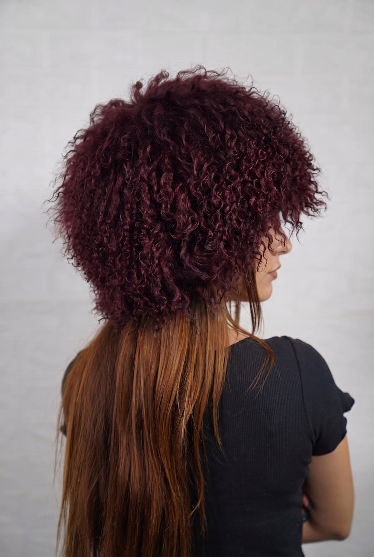 Mongolian Sheepskin Hat Burgundy — Curly Lamb Fur, One Size three-quarter back view showing the deep oxblood burgundy curls covering the crown and nape — Greek craftsmanship, TatiFurs