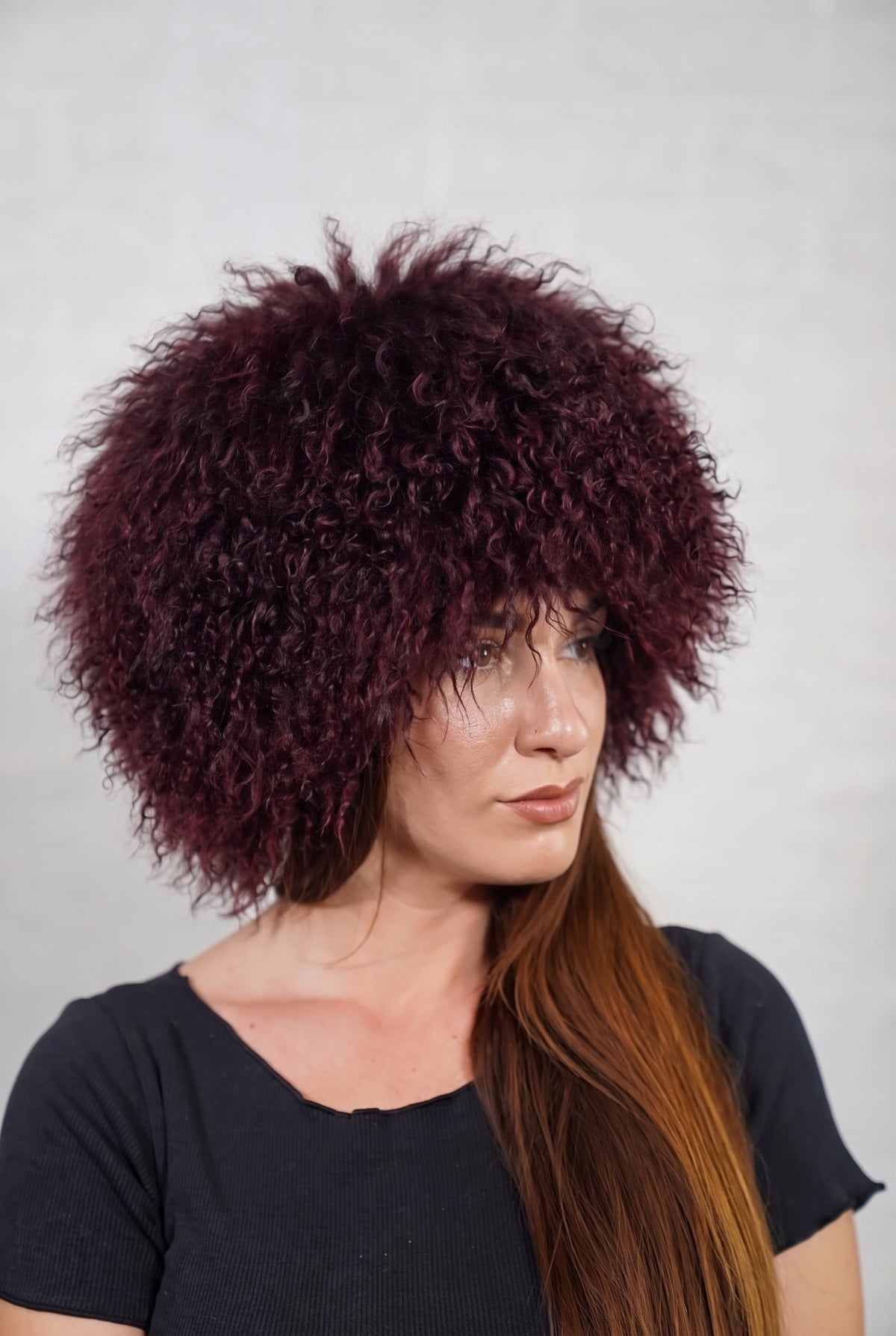 Mongolian Sheepskin Hat Burgundy — Curly Lamb Fur, One Size in profile displaying the volume and length of the deep oxblood burgundy curly sheepskin pile over the ear — TatiFurs