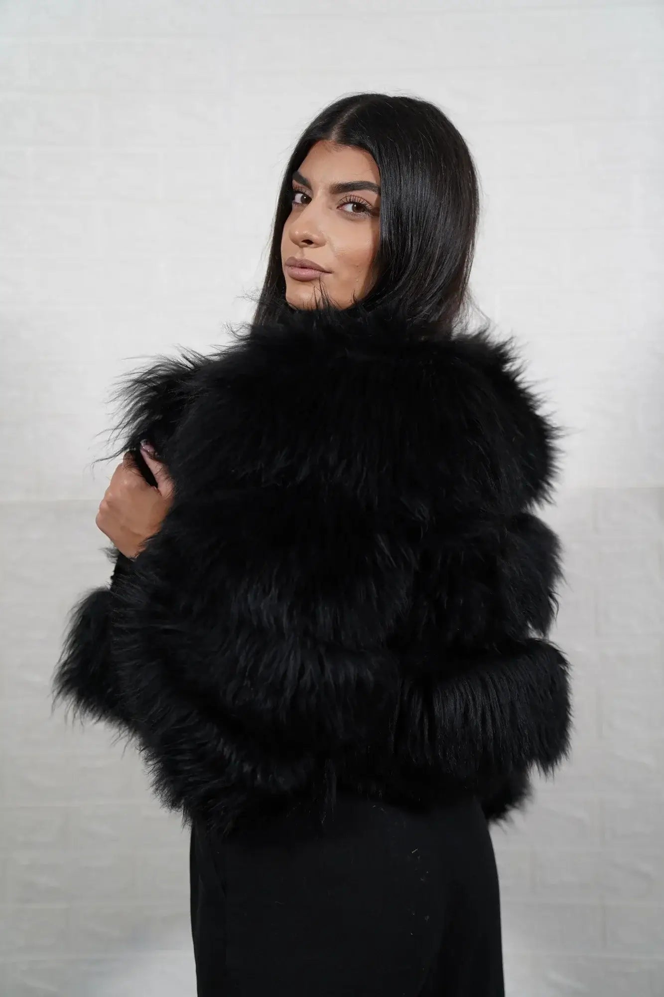 Alpaca fur jacket black shown from the side displaying cropped above waist bomber silhouette and horizontal leather framed black alpaca rows — Greek craftsmanship, TatiFurs

