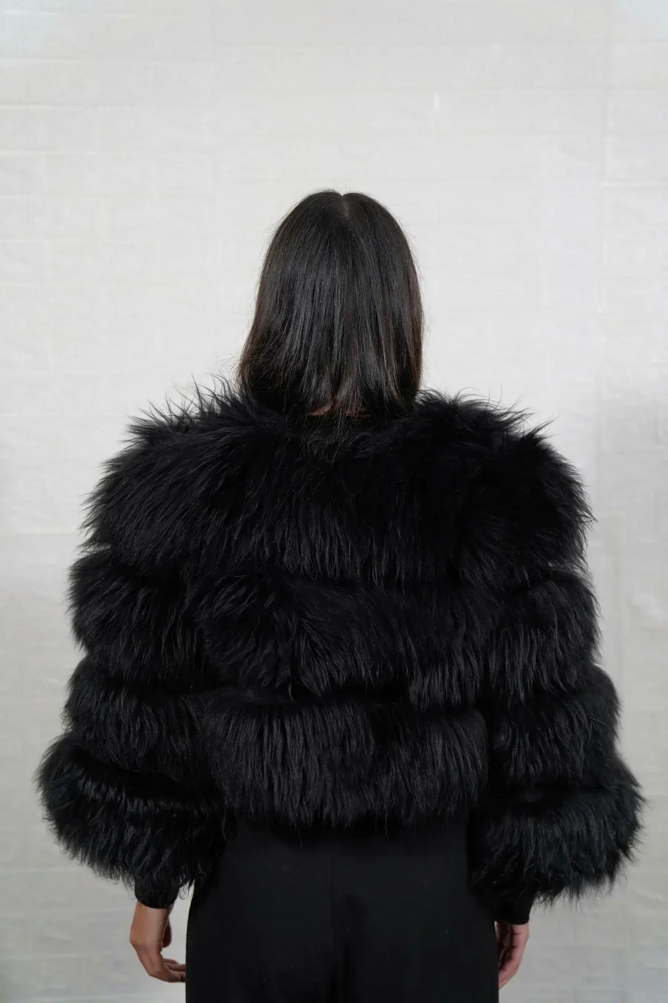 Alpaca fur jacket black shown from the back displaying full cropped bomber silhouette and horizontal leather strip construction across black alpaca rows — Greek craftsmanship, TatiFurs
