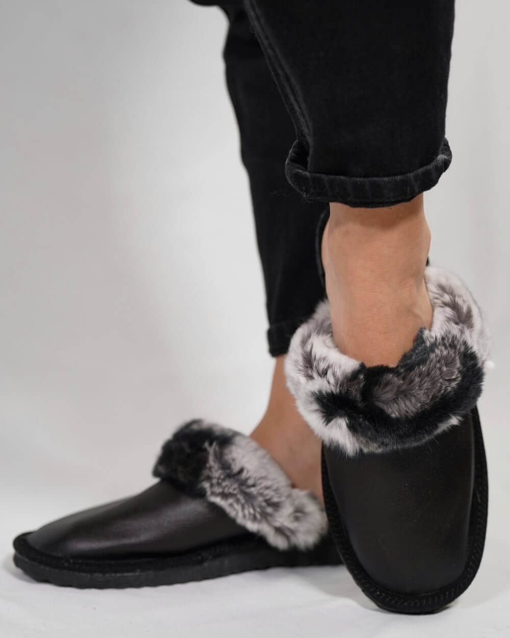 Sheepskin Wool Leather Fur Slippers Black with Gray Top worn with black jeans, showcasing the luxurious design and comfort.
