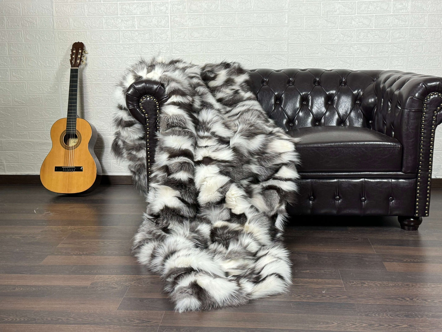 Fox Fur Blanket Throw Black Silver White - Tatifurs draped on a stylish couch with a guitar in the background.