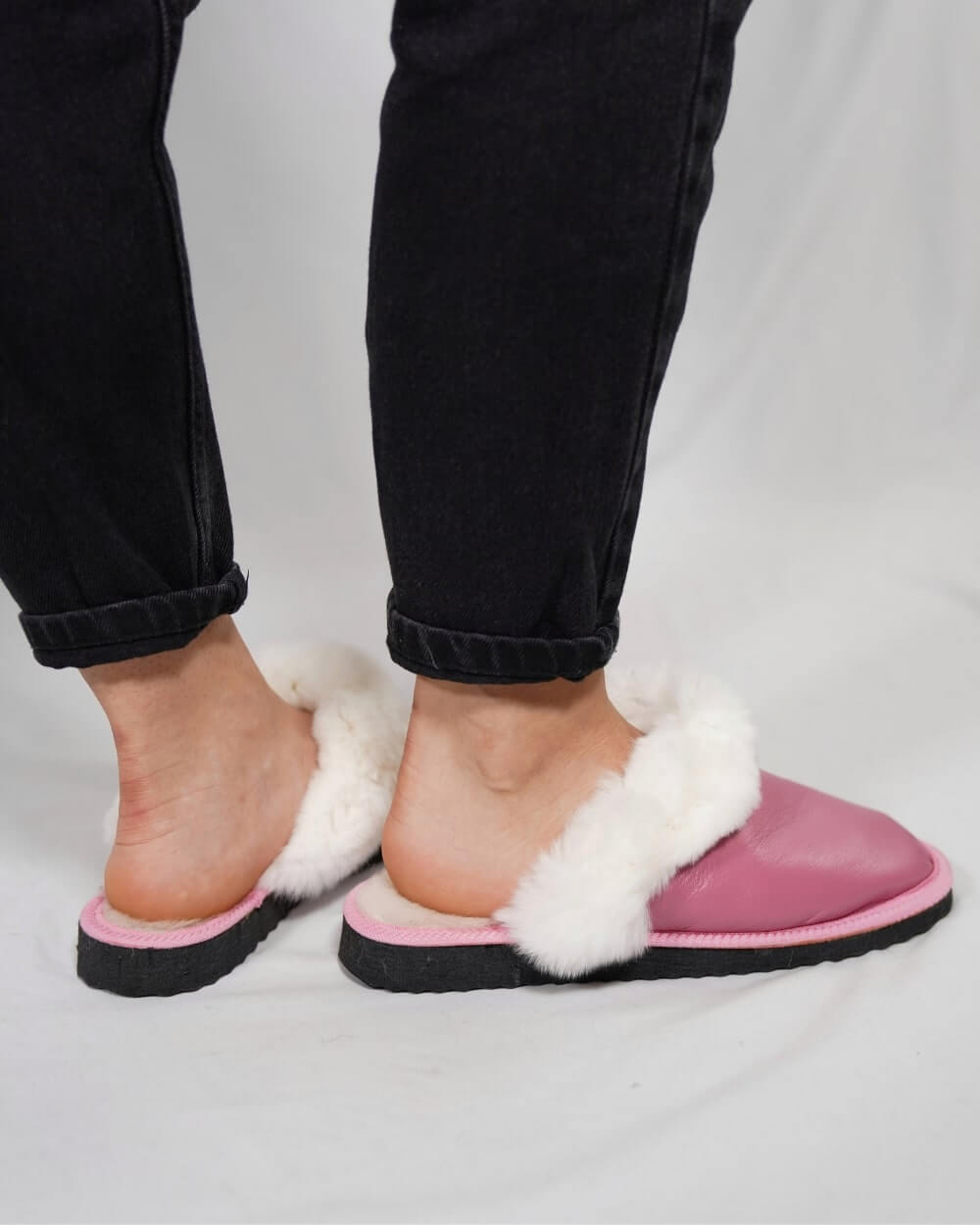 Sheepskin Wool Leather Fur Slippers Pink for Women worn on feet with black jeans, showcasing comfort and style.