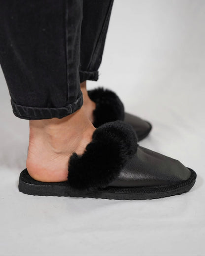 Leather Sheepskin Slippers Black - Tatifurs worn on feet against a neutral background, showcasing style and comfort.