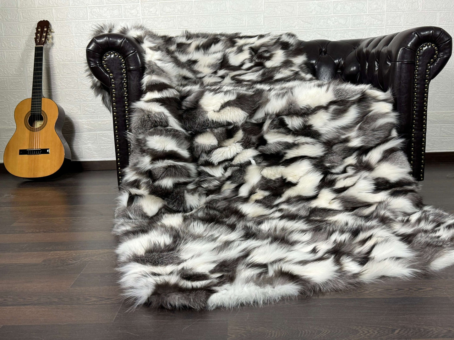 Fox Fur Blanket Throw Black Silver White - Tatifurs draped on a couch with a guitar in the background.