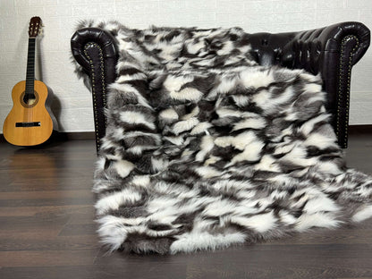 Fox Fur Blanket Throw Black Silver White - Tatifurs draped on a couch with a guitar in the background.