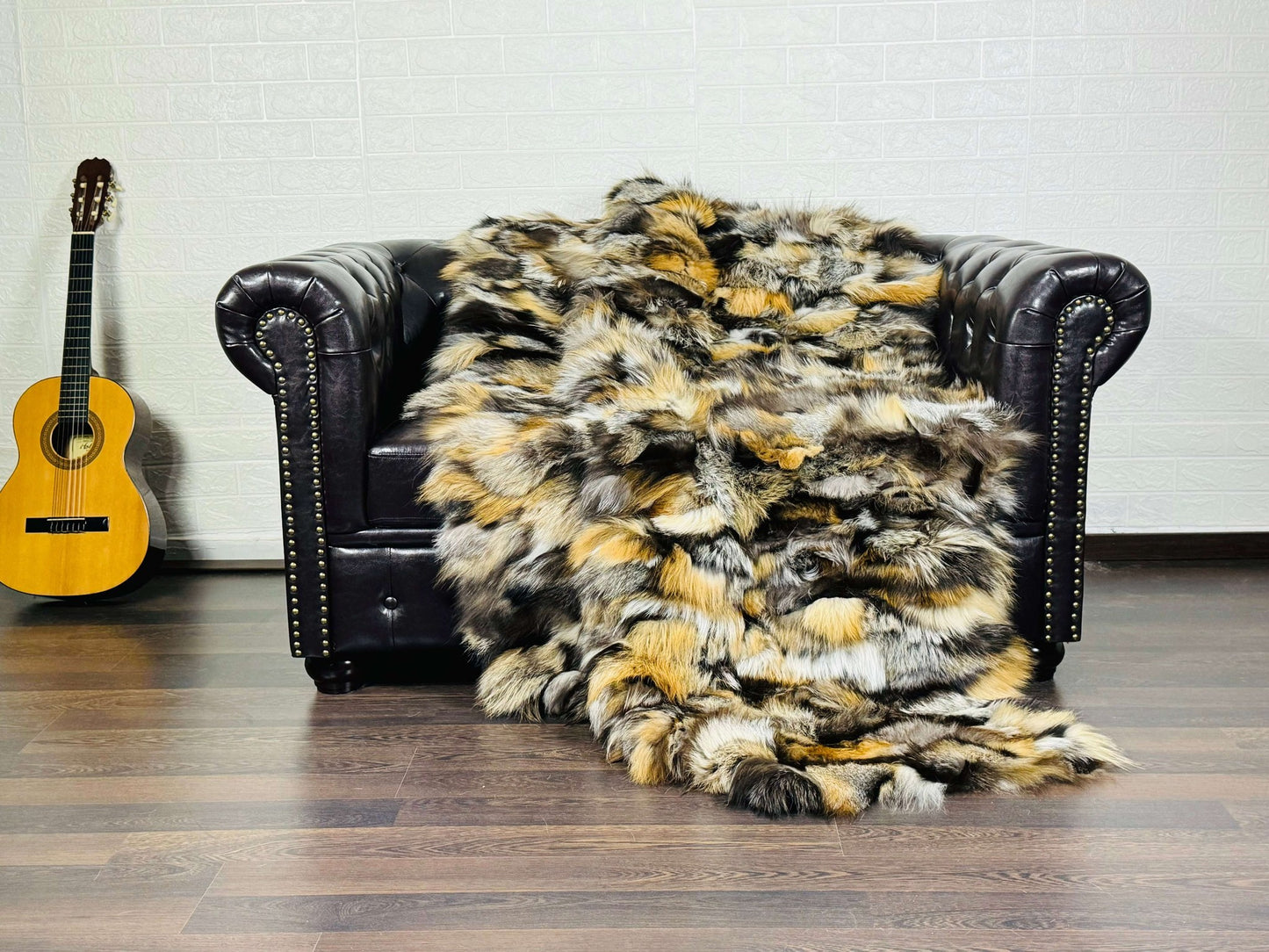 Fox Fur Blanket Throw Gross Natural - Tatifurs draped over a stylish leather couch, showcasing its unique colors and texture.