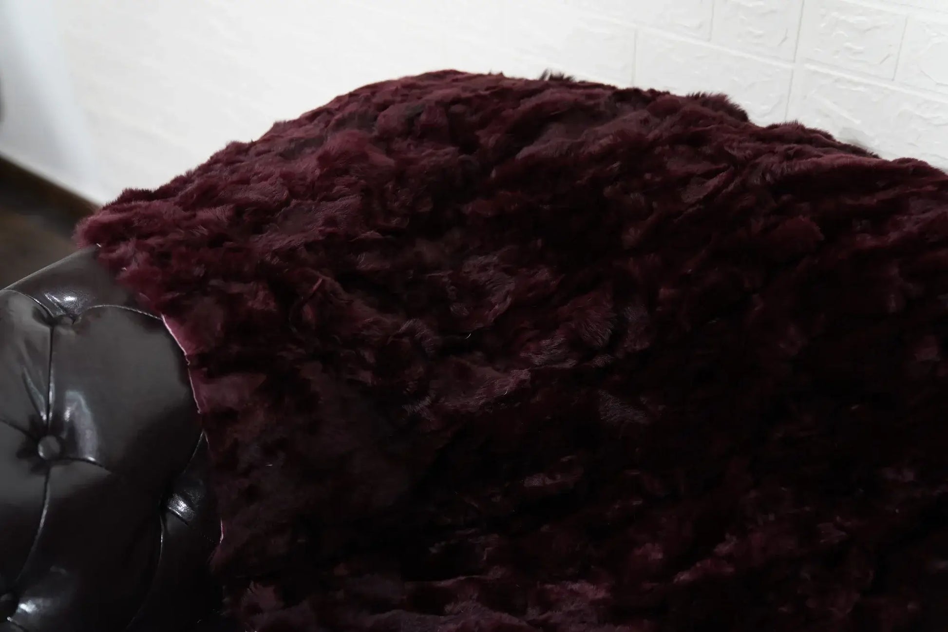 rex rabbit fur throw blanket red burgundy — draped across charcoal sofa, commanding colour contrast — Greek craftsmanship, TatiFurs
