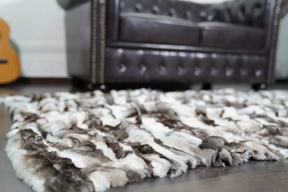rex rabbit fur throw blanket natural black white — folded over armchair, dense pile texture visible — Greek craftsmanship, TatiFurs

