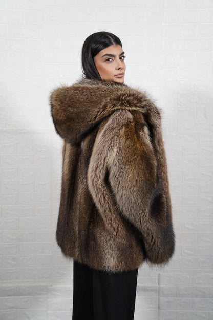Raccoon fur jacket natural brown hood worn up showing velvet lined hood interior framing face against dramatic natural brown raccoon exterior — Greek craftsmanship, TatiFurs
