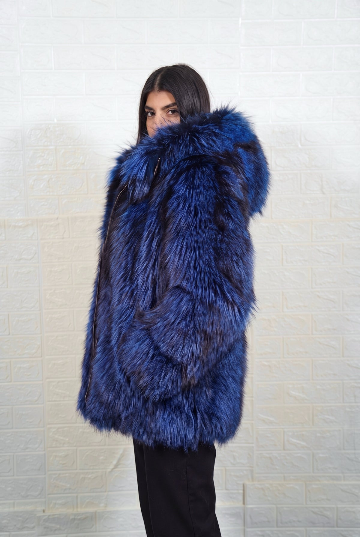 fox fur jacket blue black side profile view, chin tucked in the fur, showing electric blue over jet black fox fur and hip-covering length — Greek craftsmanship, TatiFurs