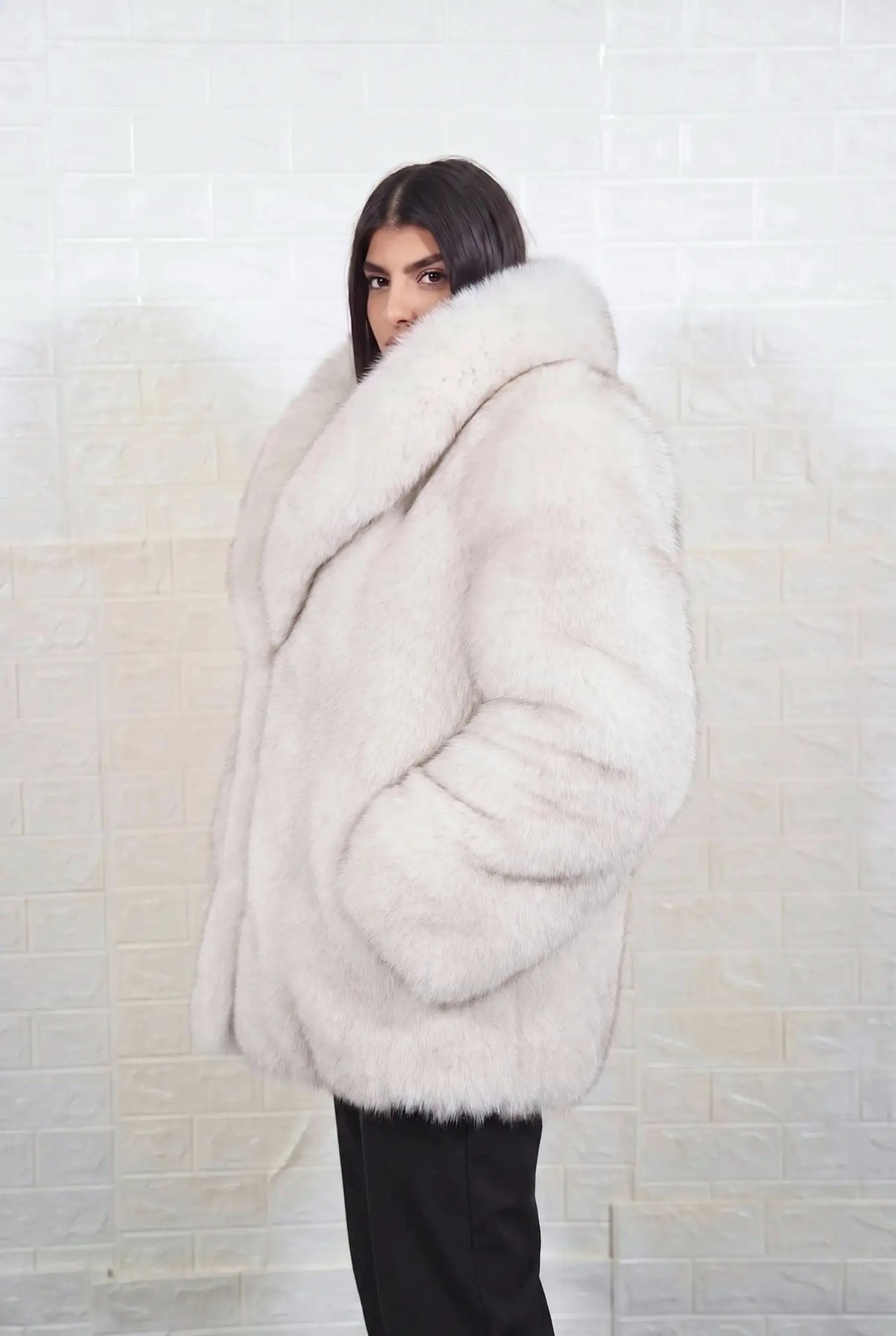 fox fur jacket blue natural side profile view, chin tucked in the fur collar, showing natural blue fox, ivory-white underfur with a soft blue-grey veil at the tips fox fur and hip-covering length — Greek craftsmanship, TatiFurs