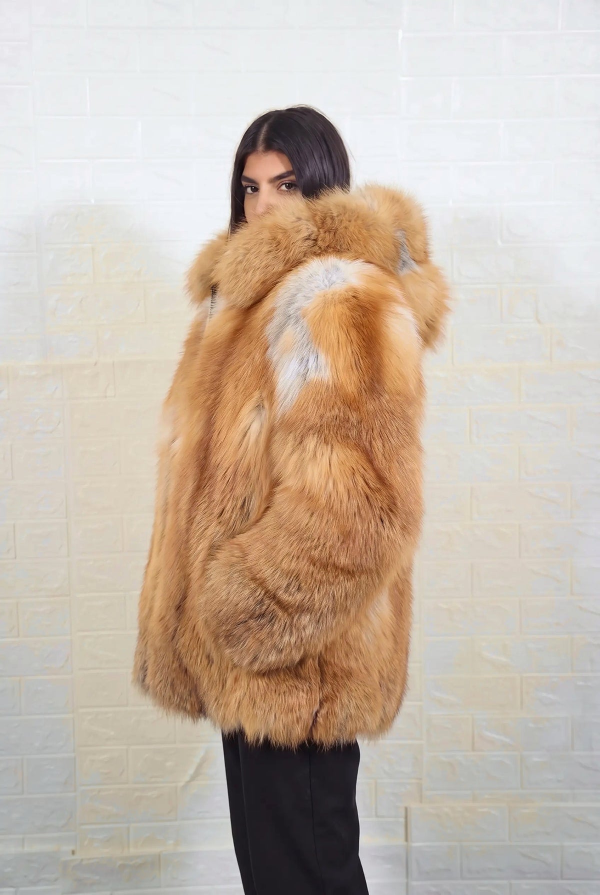 fox fur jacket golden natural side profile view, chin tucked in the fur, showing natural golden fox, warm amber-gold with cream and pale silver highlights fox fur and hip-covering length — Greek craftsmanship, TatiFurs