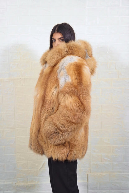 fox fur jacket golden natural side profile view, chin tucked in the fur, showing natural golden fox, warm amber-gold with cream and pale silver highlights fox fur and hip-covering length — Greek craftsmanship, TatiFurs