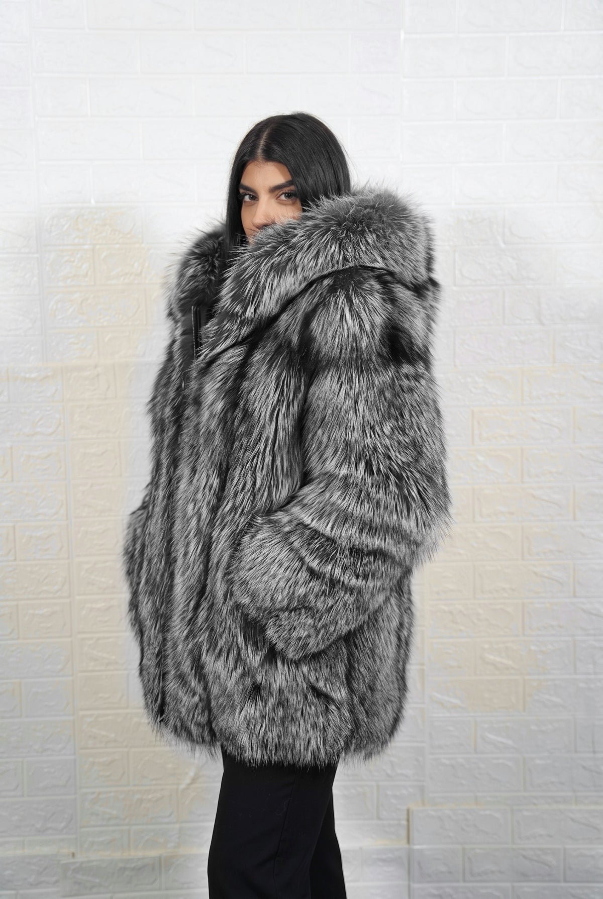 fox fur jacket silver natural side profile view, chin tucked in the fur, showing natural silver fox, black base with silver-white tips fox fur and hip-covering length — Greek craftsmanship, TatiFurs