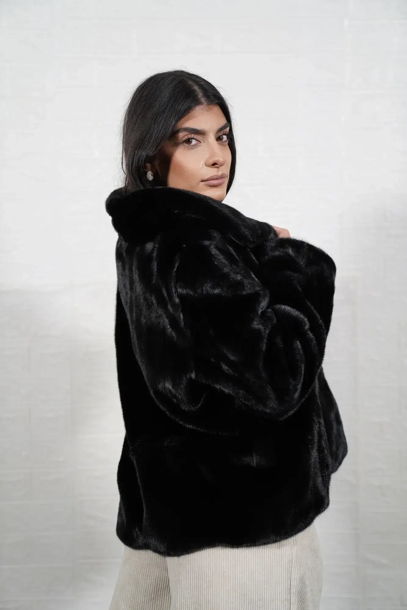 Mink fur jacket black shown from the side displaying hip level silhouette and uniform flat black solid pattern mink surface — Greek craftsmanship, TatiFurs
