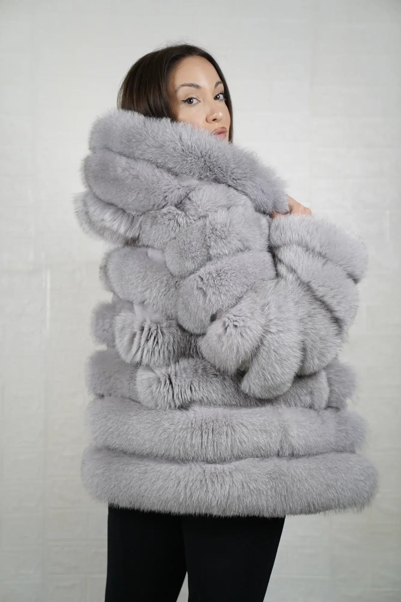 Gray fox fur jacket hood worn up showing velvet lined hood interior framing face against cool atmospheric gray fox rabbit trim exterior — Greek craftsmanship, TatiFurs
