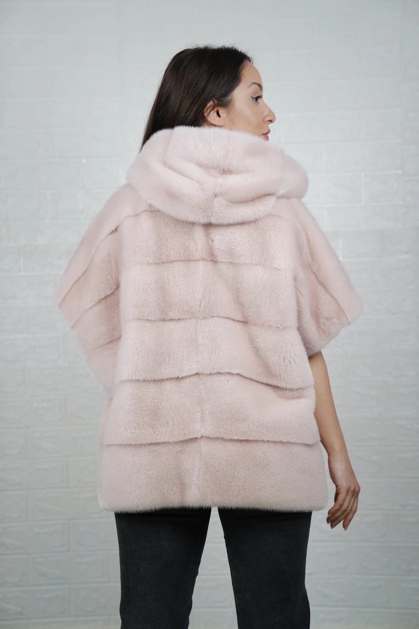 Mink fur cape pink shown from the back displaying hooded short sleeved silhouette and fluid skin on skin soft pink mink drape
