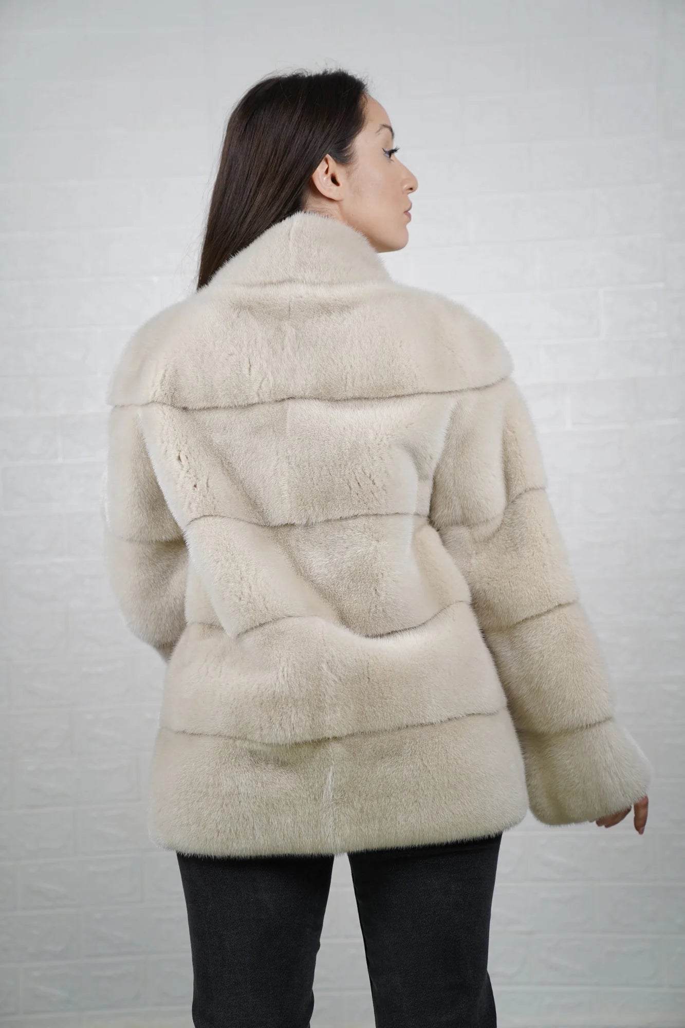 Mink fur jacket light beige shown from the back displaying mid length skin on skin construction and warm luminous light beige mink flow
