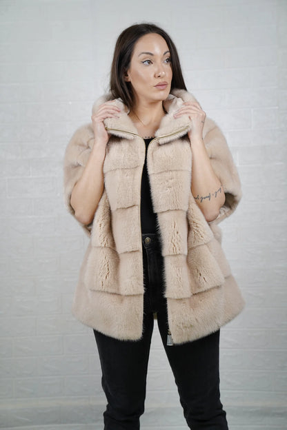 Mink fur cape beige worn over evening dress showing elegant hooded short sleeved silhouette and warm luminous beige tone
