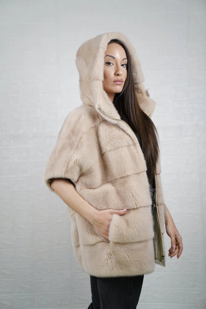 Mink fur cape beige detail shot showing warm pelt consistency and luminous beige tone from hood to sleeve hem
