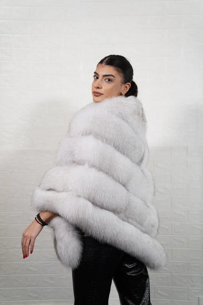 Fox fur poncho blue natural shown from the back displaying full hip level poncho silhouette and horizontal rabbit trim construction across natural blue fox rows — Greek craftsmanship, TatiFurs

