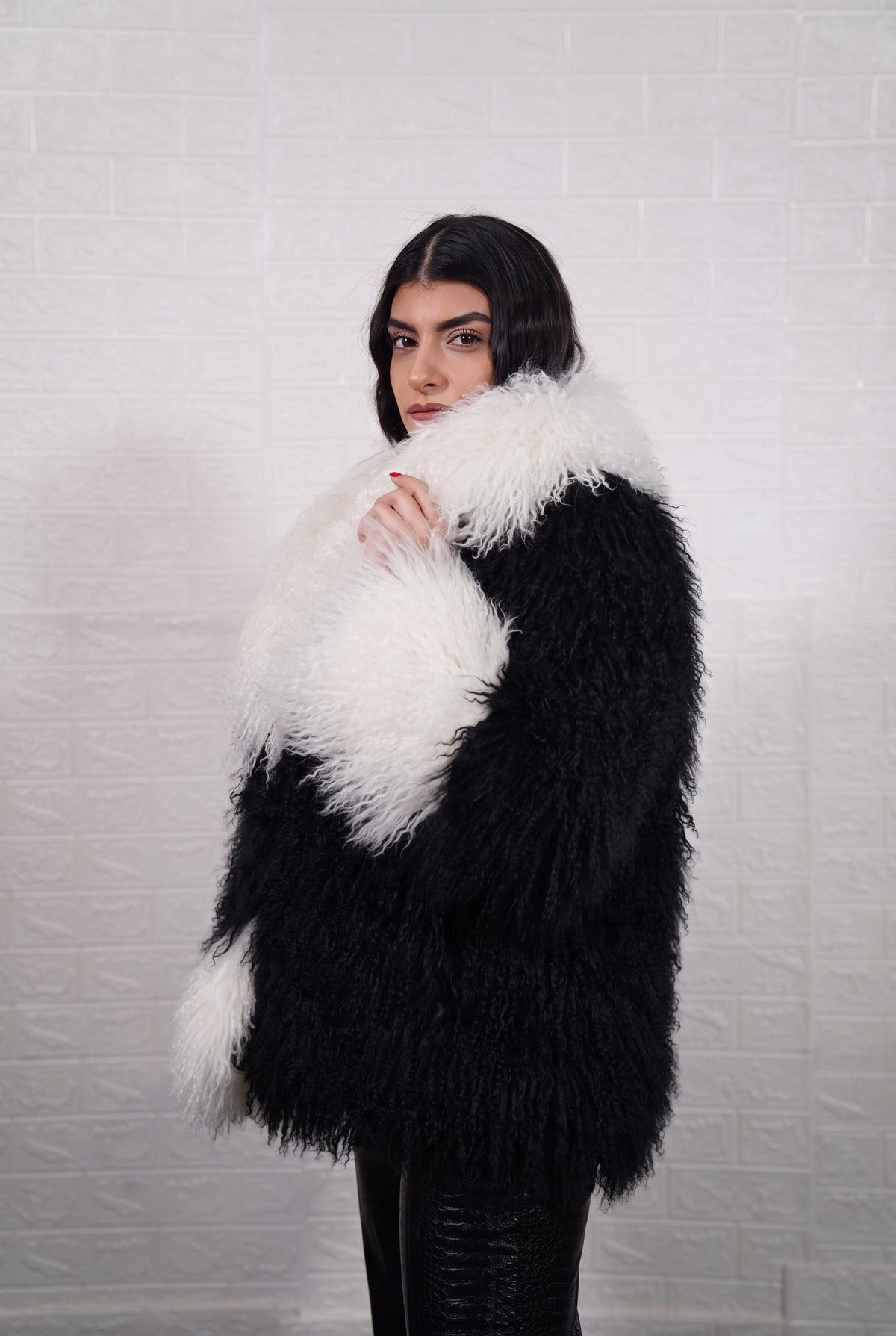 Mongolian jacket black and white shown from the side displaying hip level silhouette and jet black with ivory white long curly Mongolian wool — Greek craftsmanship, TatiFurs