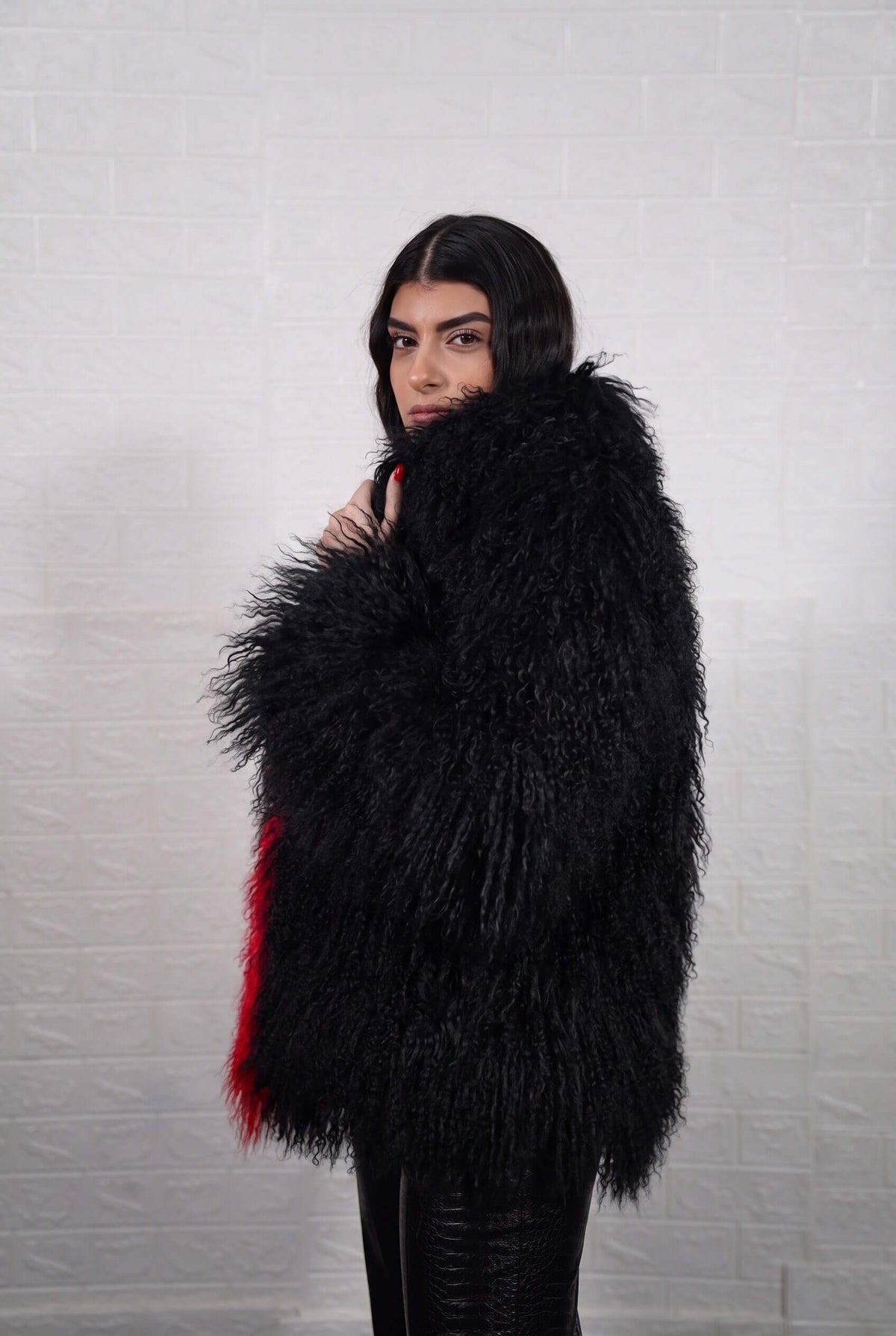 Mongolian jacket red black shown from the side displaying hip level silhouette and bold scarlet red with jet black long curly Mongolian wool — Greek craftsmanship, TatiFurs