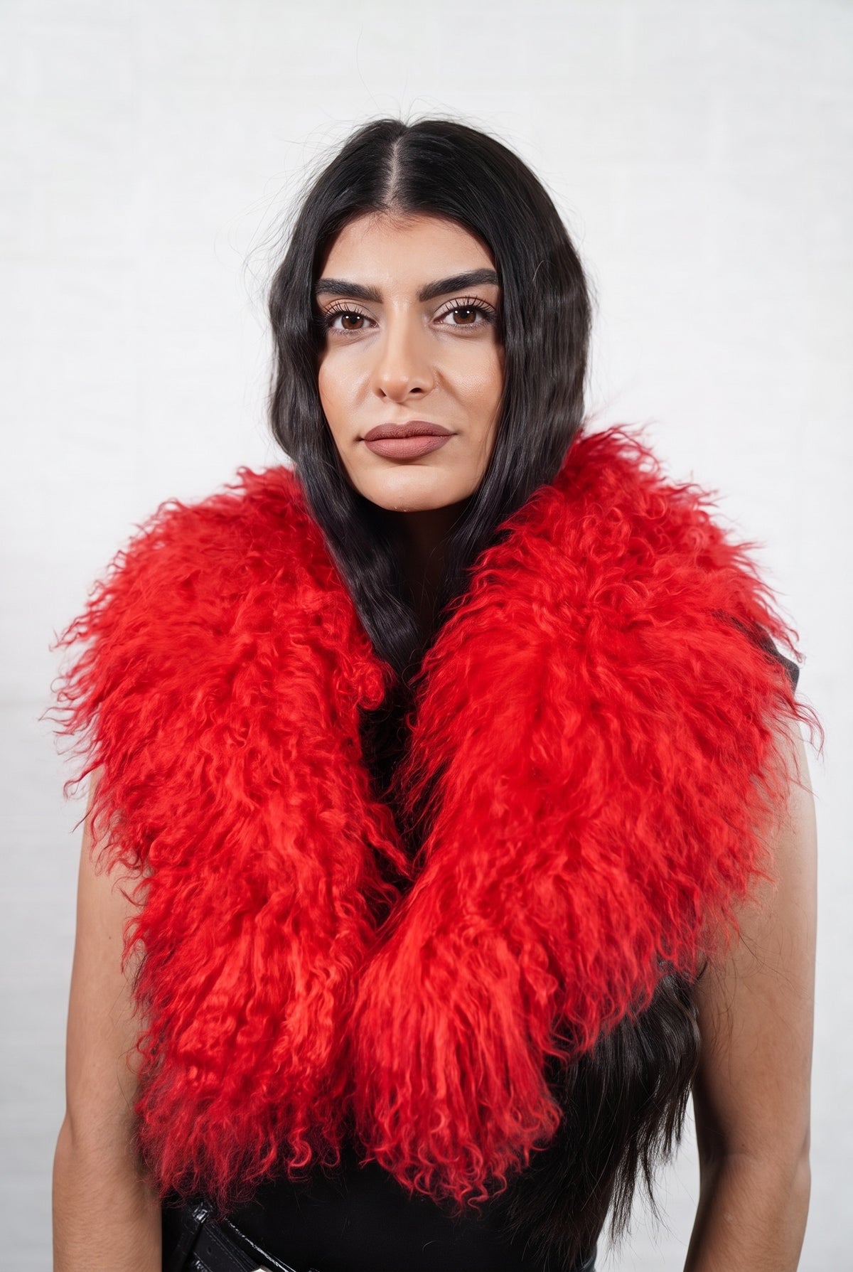 Mongolian Sheepskin Collar Red — Curly Lamb Fur worn by a woman, front view of the long curly vivid scarlet red Tibetan lamb fur framing the face and shoulders, TatiFurs