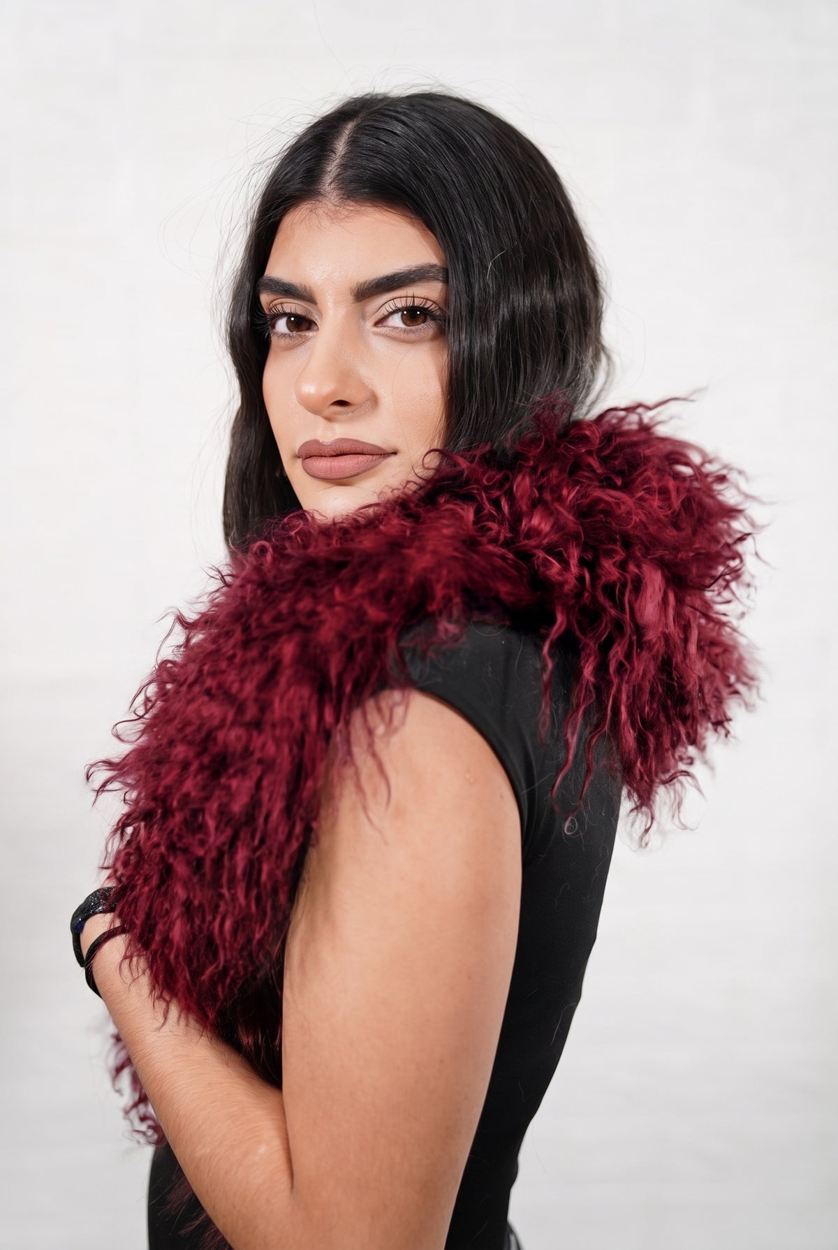 Mongolian Sheepskin Collar Burgundy — Curly Lamb Fur three-quarter view over the shoulder, volume of the deep oxblood burgundy Mongolian lamb curls around the neck — handmade in Greece, TatiFurs