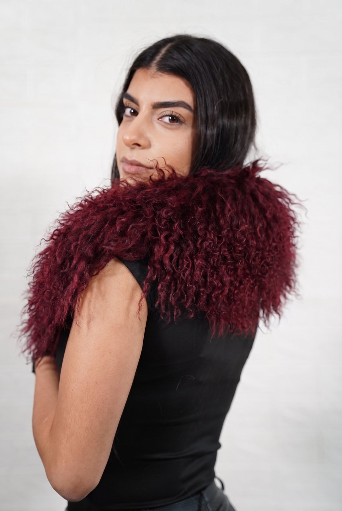 Mongolian Sheepskin Collar Burgundy — Curly Lamb Fur seen from behind, deep oxblood burgundy curly sheepskin wrapped high around the neck and shoulders — TatiFurs