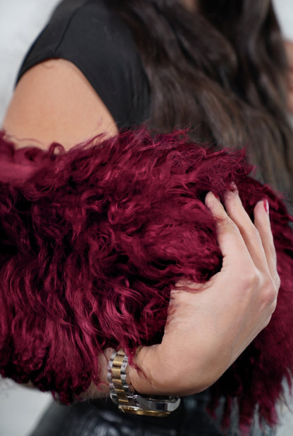 Mongolian Sheepskin Collar Burgundy — Curly Lamb Fur close-up of the dense deep oxblood burgundy Tibetan lamb curls held in the hand — TatiFurs
