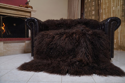 Mongolian Blanket Throw Dark Brown — Wool Sheepskin Full Skin spread across the leather sofa showing the whole deep espresso dark brown Mongolian wool surface — Greek craftsmanship, TatiFurs