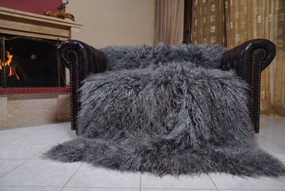 Mongolian Blanket Throw Gray — Wool Sheepskin Full Skin spread across the leather sofa showing the whole charcoal grey Mongolian wool surface — Greek craftsmanship, TatiFurs