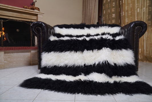 Mongolian Blanket Throw Black White Striped — Wool Sheepskin spread across the leather sofa showing the whole jet black and pure white Mongolian wool surface — Greek craftsmanship, TatiFurs
